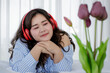 © Bangkok Click Studio - Asian young happy calm fat overweight woman lay down with happy smiling deep emotion peacefully while listening to music from big red earphones use playlist from black tablet at home in bedroom