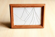 Photo frame with broken glass on a light wooden surface.