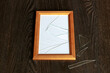 A wooden photo frame with broken glass lies on the table.