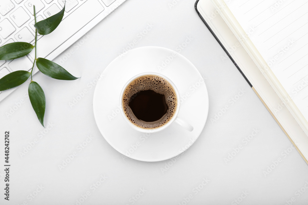 Cup of coffee, notebook and keyboard on grey background