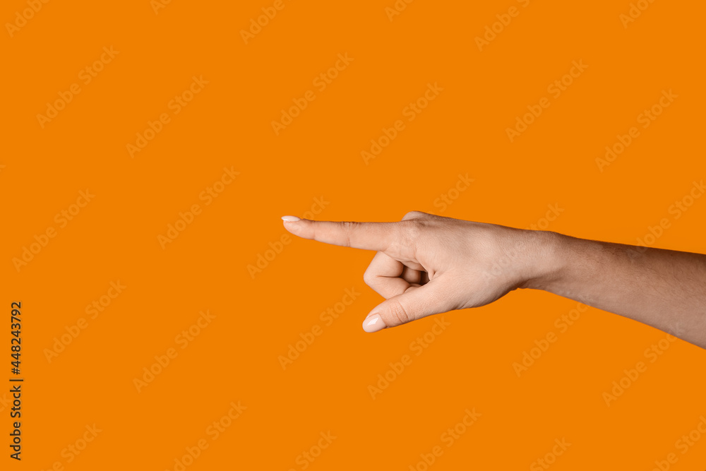 Woman pointing at something on color background
