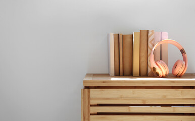 Headphones with books on shelf near light wall