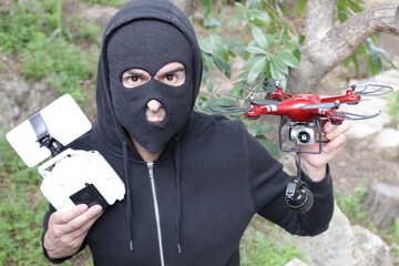 Man wearing balaclava holding a drone