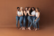 Group of multi-ethnic women in casuals posing together against a brown background