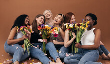 Six Women Of Different Ages And Body Types Holding Bouquets While Sitting In Studio Against A Brown Background