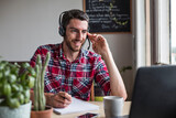 Fototapeta Sypialnia - Man working from home in conference call with colleagues using headset