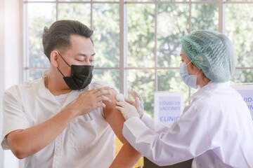 Wall Mural - Portrait of man looking at while getting covid vaccine in clinic or hospital, with hand nurse injecting vaccine to get immunity for protect virus. teenager wearing protective mask.