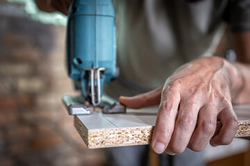 Close-up process of cutting wood board with jigsaw.