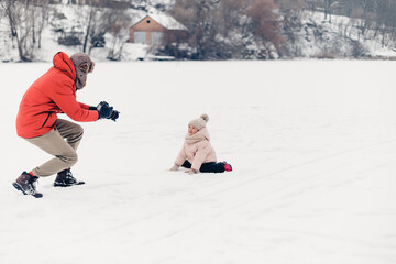 Canvas Print - Handsome bearded young dad and his little cute daughter are having fun outdoor in winter. Enjoying spending time together. Family concept