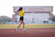 © EduLife Photos - A young Asian woman athlete runner jogging on running track in city stadium in the sunny morning to keep fitness and healthy lifestyle. Young fitness woman runs on stadium track. Sport and recreation