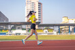 © EduLife Photos - A young Asian woman athlete runner jogging on running track in city stadium in the sunny morning to keep fitness and healthy lifestyle. Young fitness woman runs on stadium track. Sport and recreation