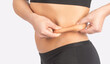 © Dimid - Girl pulls the skin on the abdomen, showing the body fat in the abdominal area and sides. Treatment and disposal of excess weight, the deposition of subcutaneous fat.