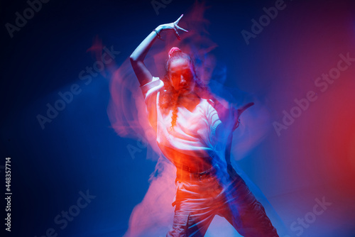 Cool mixed race young girl moving in colourful studio light. Long exposure. Contemporary stylish advertising photo