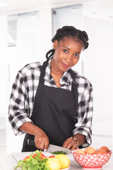 Afro american woman chopping parsley while smiling at the camera