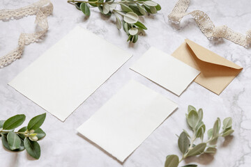 Wedding blank cards laying on a marble table decorated with eucalyptus branches