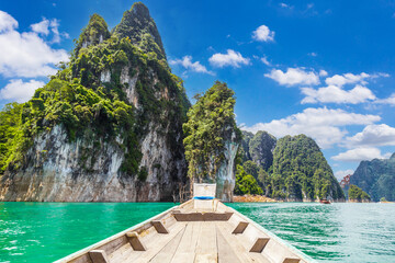 Wall Mural - Wooden Thai traditional long-tail boat on a lake with mountains at Ratchaprapha Dam or Khao Sok National Park, Thailand