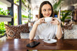 © dianagrytsku - Beautiful smiling woman drinking coffee at cafe. Portrait of mature woman in a cafeteria drinking hot cappuccino and looking at camera.
