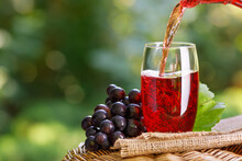 Grape Juice Pouring Into Glass From Jug