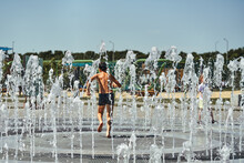 The Child Plays In The Fountain In The Hot Summer