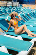 © Andrii - A young sexy girl in glasses and a hat is smiling happily and sunbathing on a sun lounger on a sunny day. Happy vacation vacation. Summer holidays and tourism.