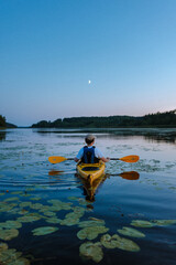 man kayaking in sea in finland summer night time  holiday fun travel to europe sustainable travel carbon sink moonlight negative space corporate background