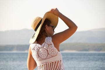 Woman in white lace dress holds her hat