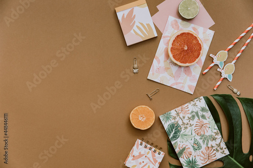 Flat lay tropical jungle Monstera leaves, paper notebook, summer background. Top view feminine diary and stationery on home office desk