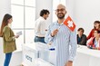 © Krakenimages.com - Young swiss voter man smiling happy holding switzerland flag standing by ballot at vote center.