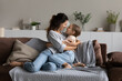 © fizkes - Happy mom and little daughter girl hugging, resting on couch, enjoying time together at home. Mother cuddling, embracing kid with love, tenderness. Family, being parent, motherhood concept