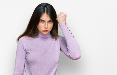 Sticker - Young beautiful teen girl wearing turtleneck sweater angry and mad raising fist frustrated and furious while shouting with anger. rage and aggressive concept.