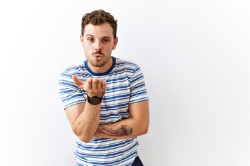 Poster - Handsome young man standing over isolated background looking at the camera blowing a kiss with hand on air being lovely and sexy. love expression.