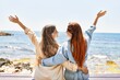 Young lesbian couple of two women in love at the beach. Beautiful women together at the beach in a romantic relationship sitting on a bench