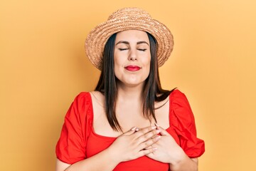 Sticker - Young hispanic woman wearing summer hat smiling with hands on chest with closed eyes and grateful gesture on face. health concept.