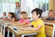 © JackF - Schoolkids studying in classroom during lesson. Female teacher staning amongst desks.