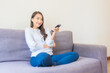 © siraphol - Portrait beautiful young asian woman use remote for change channel