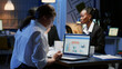 © DC Studio - Business entrepreneur woman writing financial statistics analyzing graphs presentation on computer whilebcoworkers brainstorming ideas. Multi ethnic business team working in meeting room in evening