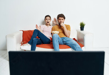 Wall Mural - young couple sitting on the couch popcorn watching a movie relaxing