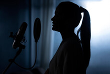 SILHOUETTE OF A WOMAN SINGING ON MIC