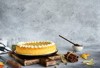 Wall Mural - Delicate cheesecake with pumpkin on a wooden board on a concrete background.