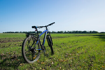 Wall Mural - bike stands on in the field. A mountain bike stands on a field path with green grass. cycling. Mountain bike. outdoor cycling activities. space for text. editorial, Ukraine, Kiev region 2020