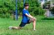 © soleg - teenage boy exercising outdoors, sports ground in the yard, he squats and does a warm-up, healthy lifestyle