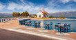 © Andrew Mayovskyy - Romantic summer view of of Saint Spiridon, Greek Orthodox church and empty tables of smal coastal resraurant. Beautiful outdoor scene of Elafonisos island, Greece. Bright Mrditerranean seascape.