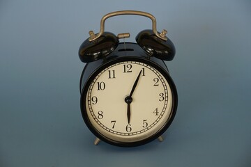 alarm clock and a cup of coffee against blue background