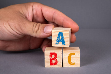 Wall Mural - ABC alphabet wooden blocks and a man's hand on a gray background