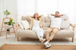 © New Africa - Couple relaxing on sofa in living room