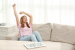 © New Africa - Beautiful young woman stretching on sofa at home, space for text