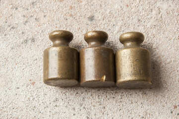 Wall Mural - Three antique bronze weights for scales on concrete background.