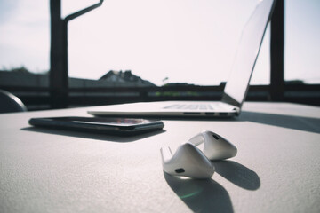 Wall Mural - laptop, mobile phone and earphones on the white table with hard shadow