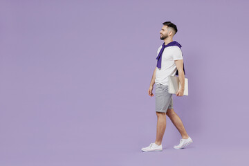 Sticker - Full size body length side view young brunet man 20s wears white t-shirt purple shirt hold under hand laptop pc computer go move stroll look ahead isolated on pastel violet background studio portrait