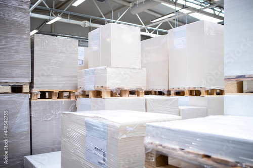 Printing house warehouse interior with large piles of blank sheets for print.